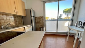 A modern kitchen with a large window, a sink, and a dining area with a table and chairs. - Seafront apartment with private parking (La Ciotat)