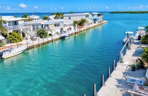A waterfront property with a dock, boats, and a clear view of the ocean. - Open Water View from porch , golf cart, dock, bikes, kayaks, trailer parking  (Cudjoe Key)