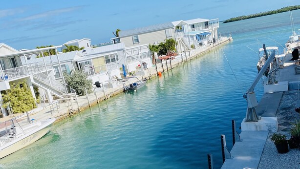 Una propiedad frente al agua con muelle, un barco y un edificio de varios niveles y balcones.