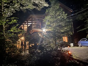 A wooden cabin with a balcony, surrounded by dense foliage. - Romantic,Cozy Log Cabin, Hot Tub, WiFi, pool table (topton)