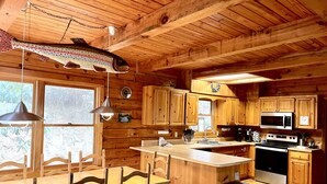 Ein Holzblockhaus-Innenraum mit Essbereich, Küche und einem großen Fisch, der von der Decke hängt.