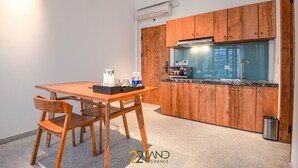 A compact kitchen with wooden cabinets, a countertop, and a sink. There is a table with chairs and a coffee maker. - Athena Suites R101 (Hanoi)