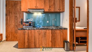 A compact kitchen with wooden cabinets, a black countertop, and a stainless steel sink. - Athena Suites R101 (Hanoi)