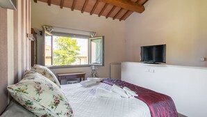 Un dormitorio con una cama, un ventanal, un espejo, un televisor y un techo de madera.