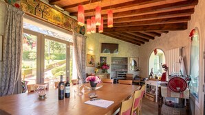 Un interior rústico con techo de madera, una zona de comedor con mesa para dos y una cocina con electrodoméstico rojo.