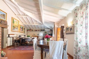 A dining area with a round table, chairs, a red rug, and a ceiling with exposed beams.