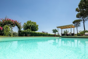A clear swimming pool with a pergola and seating area, surrounded by lush greenery and trees. - Villa Collesole by MMega (Rignano sull'Arno)