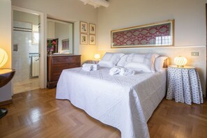 A bedroom with a bed, bedside tables, a dresser, a mirror, and a wall with framed pictures.