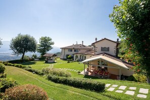 Une grande maison avec un jardin, une terrasse et une vue sur les montagnes.