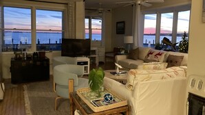 A living room with a television, sofa, and a view of the water. - Bayfront Bungalow (Cape May Court House)