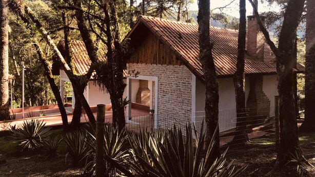 Un bâtiment rustique, doté d’un toit en tuiles, entouré d’arbres et de plantes.