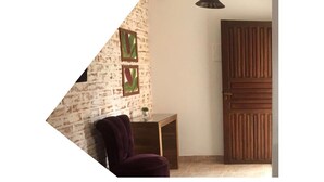 Une pièce avec un mur en briques, une porte en bois et une petite table sur laquelle est posée une plante.