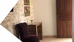 A room with a brick wall, a wooden door, and a small table with a plant.