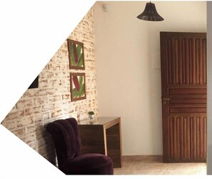 A room with a brick wall, a wooden door, and a small table with a plant. - CHALET BORDEAUX (Monte Verde)