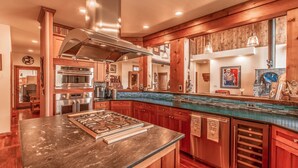 A modern kitchen with wooden cabinets, stainless steel appliances, and a large island with a gas range. - Cutbow Bend (Livingston)