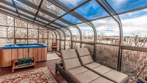 A sunroom with a curved glass ceiling, a hot tub, a lounge area with a sofa, and a patterned rug. - Cutbow Bend (Livingston)