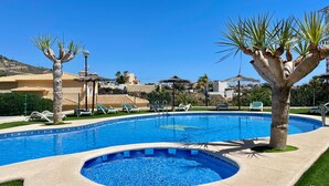 Una piscina con lettini, palme e cielo azzurro limpido.