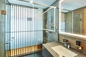 Un baño moderno con cabina de ducha de vidrio, un espejo grande y una encimera de granito.
