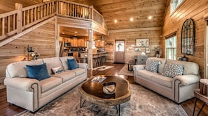 A spacious living area with two sofas, a coffee table, and a staircase leading to a loft.
