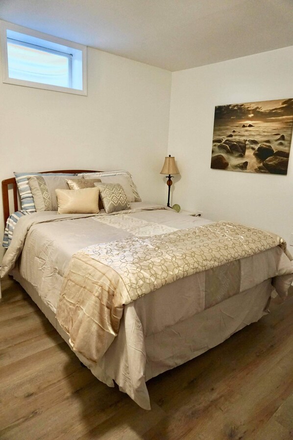Un dormitorio con cama, lámpara y un cuadro en la pared.