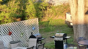 Un patio al aire libre con una parrilla, una mesa de comedor y zona de estar.