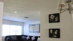 Una sala de estar con un sofá de color oscuro, una mesa de centro de madera y un cuadro de un árbol en la pared.