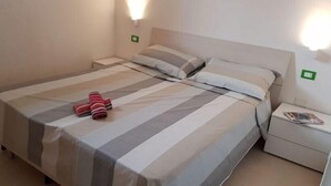 Una habitación de hotel con cama, mesitas de noche y una lámpara fijada a la pared.