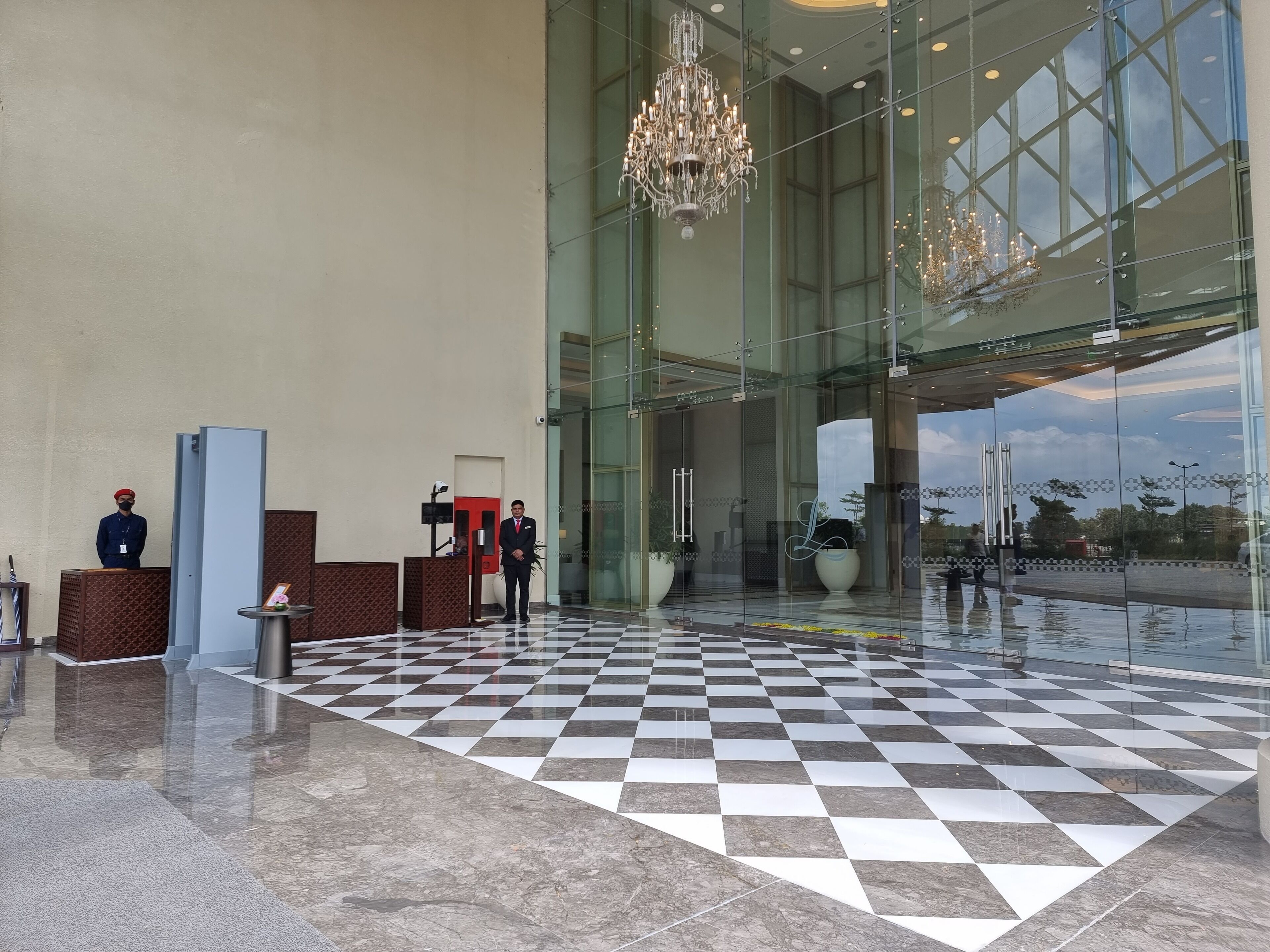 A lobby with a checkered floor, a reception desk, and a large chandelier.