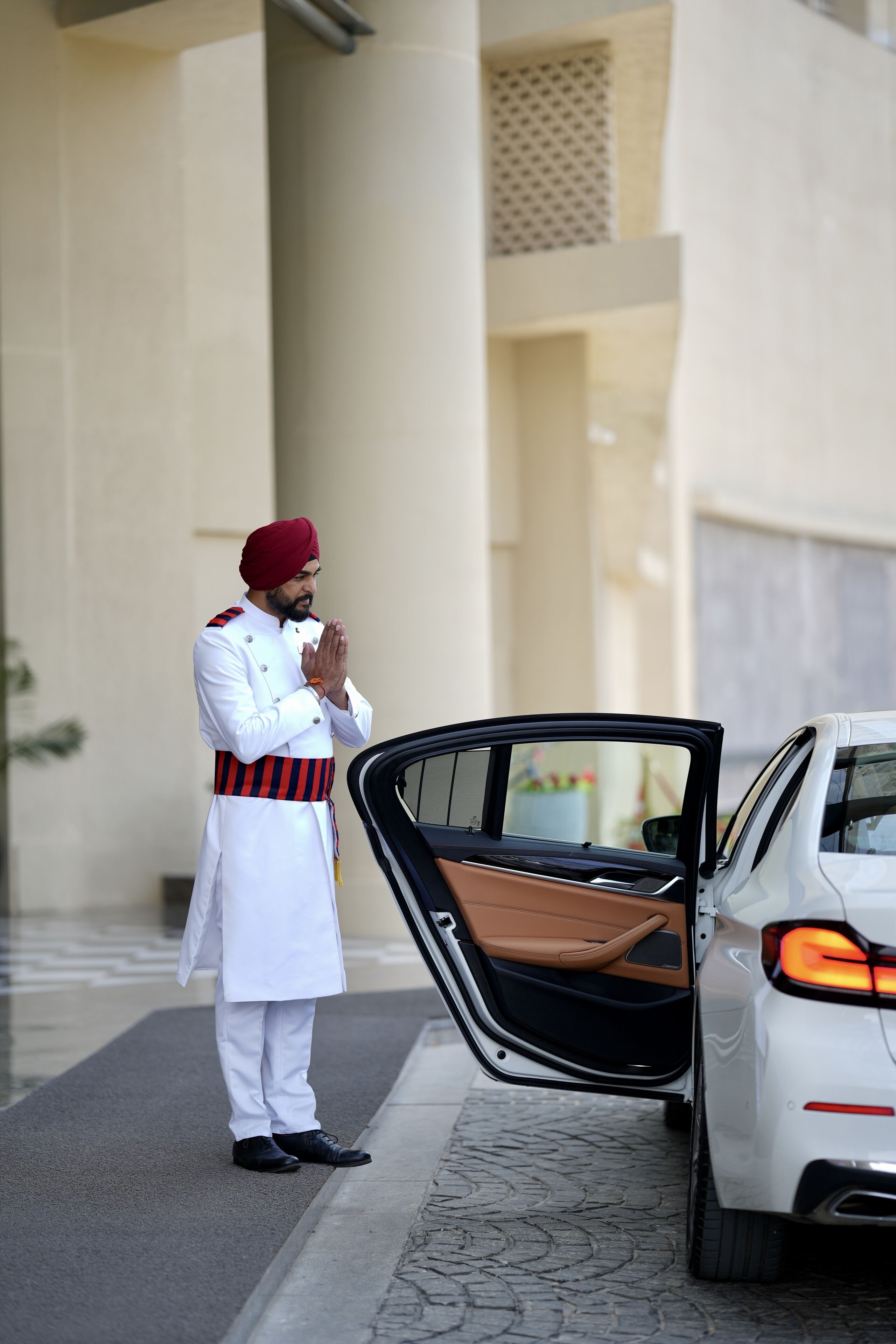 Ein Mann in Uniform steht neben einem Auto mit geöffneter Tür.