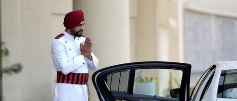 A uniformed guard standing beside a car with its door open.