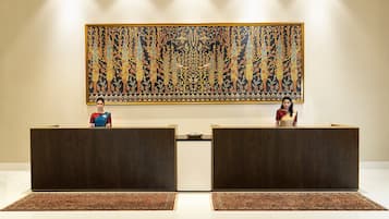 A reception area with two wooden reception desks, a large decorative tapestry on the wall, and a patterned carpet.