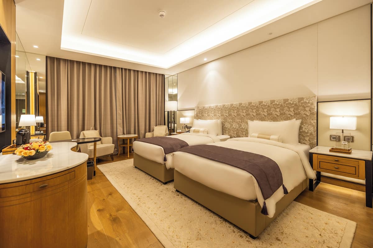 Una habitación de hotel moderna con dos camas, una zona de estar, un escritorio y un baño.