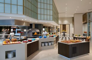 Una cocina moderna con una isla central, horno para pizza y un chef preparando comida.