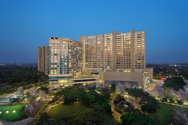 A multi-story hotel with a modern design, featuring a rooftop garden and a well-lit courtyard. - The Leela Bhartiya City Bengaluru (Bengaluru)