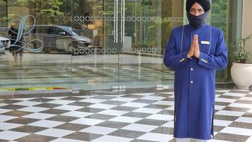 A person in traditional attire standing in front of a building with a checkered floor and glass entrance.