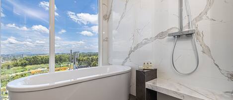 Un baño moderno con una bañera independiente, ducha y pared de mármol.