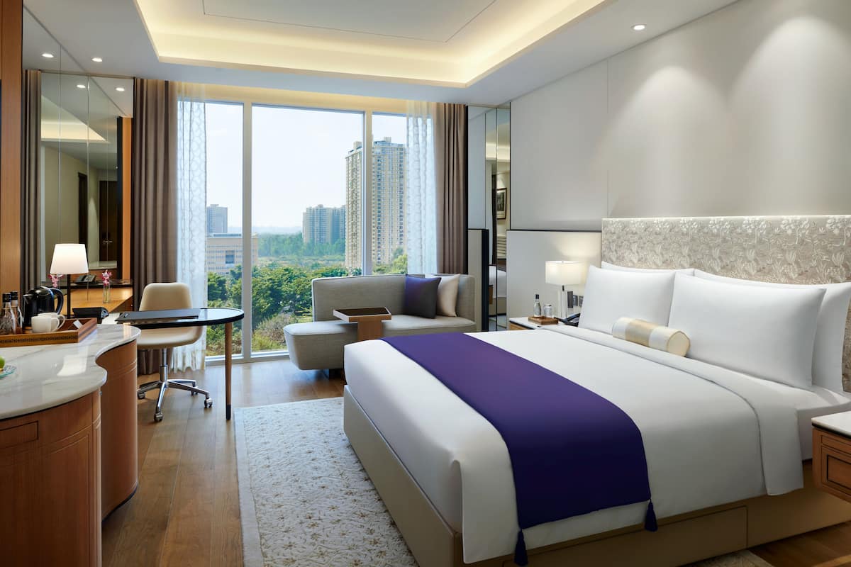 Un hotel moderno con una cama grande, un escritorio, una silla y vistas a la ciudad.
