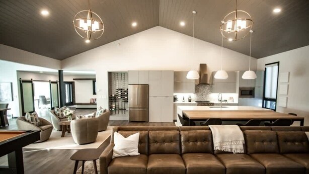 Un salón espacioso con un sofá grande, una mesa de comedor y una cocina al fondo.
