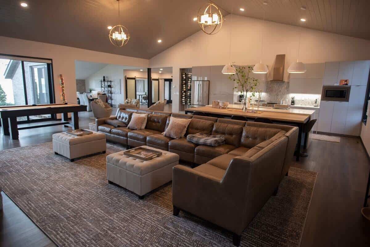 A spacious living area with a large sofa, ottomans, and a dining table.