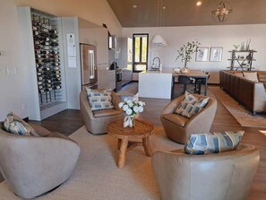Un salon moderne doté d’une cheminée, d’un coin repas et d’une cuisine avec un espace de rangement pour les bouteilles de vin.