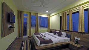 Un dormitorio con cama, televisión montada en la pared y ventana con cortinas.