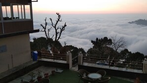 Una terraza con vistas a un paisaje montañoso y nubes abajo.
