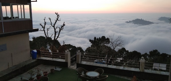 Una terraza con vistas a un paisaje montañoso y nubes abajo.
