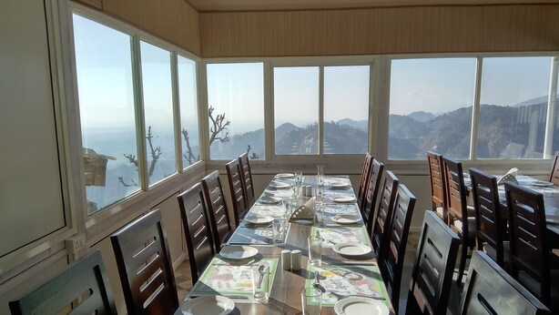 Comedor con una larga mesa dispuesta para varias personas, ventanas amplias que ofrecen vistas a la montaña y sillas de madera.