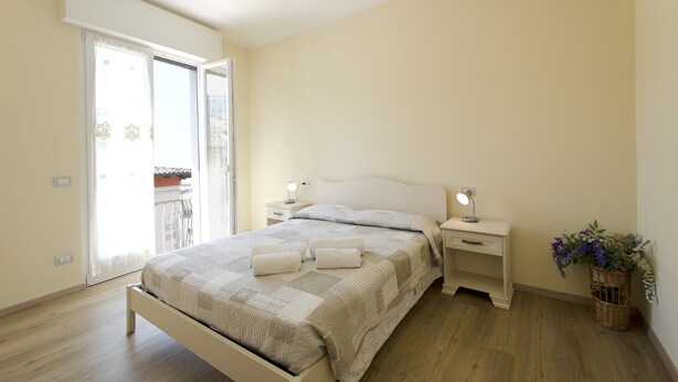 Een slaapkamer met een bed, nachtkastjes, een lamp, een raam en uitzicht.