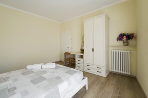 Une chambre à coucher comprenant un lit, un bureau, une chaise, une armoire et un radiateur.