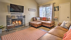 A living room with a fireplace, leather sectional sofa, and a flat-screen TV mounted above it. - Manitou Springs Escape w/ A/C & Private Deck! (Manitou Springs)