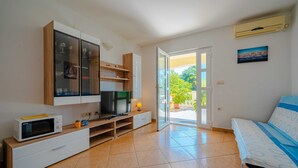 Una camera da letto moderna con un letto, una TV, un forno a microonde e una porta scorrevole in vetro che dà su un balcone.