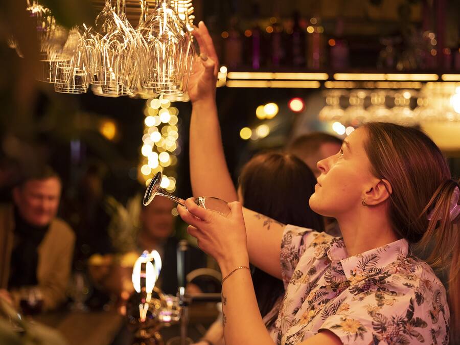 Iemand reikt naar een glas dat aan een hanglamp hangt.