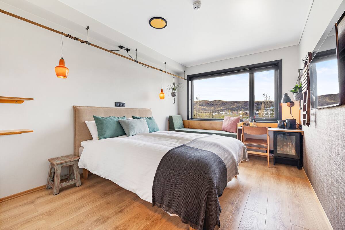 Une chambre moderne avec un grand lit, un bureau et une vue sur l’extérieur.